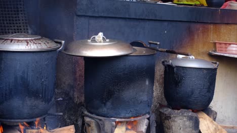 3-Große-Kochtöpfe-Auf-Einem-Holzfeuer-Mit-Nicht-Wiederzuerkennenden-Personen-Im-Hintergrund