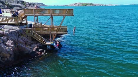 Swimmers-using-the-new-wooden-jump-tower-in-Lysekil,-Sweden