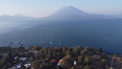 Aerial:-Atitlan-Volcano-visible-across-lake-from-Jaibalito,-Guatemala