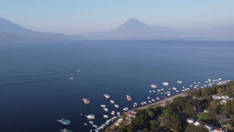 Boats-line-Jaibalito-shore-across-Lake-Atitlan-from-volcano-mountain