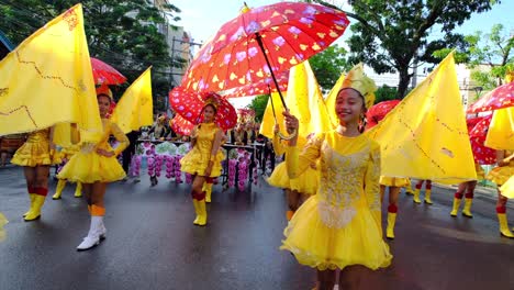 Un-Grupo-De-Niños-Vestidos-De-Amarillo-Mientras-Sostienen-Paraguas-Rojos-Y-Caminan-Hacia-El-Desfile