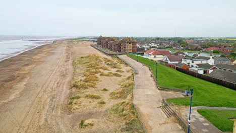 Aerial-views-present-Mablethorpe's-vibrant-atmosphere,-with-beach-huts,-sandy-beaches,-amusement-parks,-rides,-and-a-bustling-tourist-scene