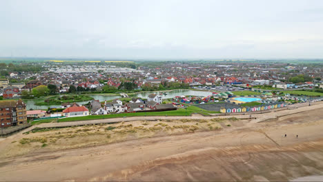 Aerial-glimpses-of-Mablethorpe,-Lincolnshire's-east-coast-retreat,-showcasing-beach-huts,-sandy-beaches,-amusement-parks,-rides,-and-tourists