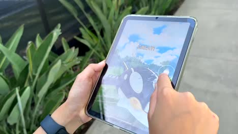 POV-Eines-Kindes,-Das-Pokemon-Go-Auf-Einem-Mobilen-Tablet-Spielt,-Während-Es-Durch-Den-Nachbarschaftspark-Spaziert