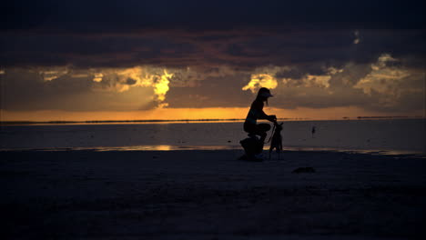 Schlanke-Lateinamerikanische-Brünette-Genießt-Den-Wunderschönen-Sonnenuntergang-Mit-Ihrem-Hund-Am-Strand-Von-Cancun,-Mexiko