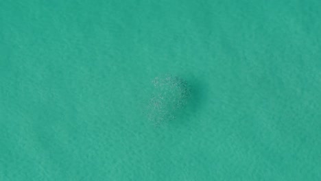 Aerial-topdown-view-of-small-fish-group-in-clean,-transparent-sea-water-blue-ocean-in-sun