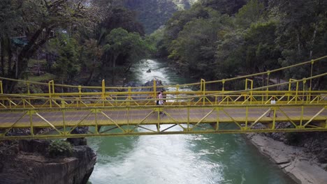 Los-Turistas-Caminan-Por-El-Puente-Amarillo-Sobre-El-Río-Semuc-Champey-En-Guatemala.
