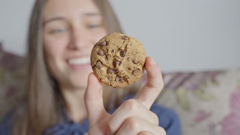 Happy-woman-holding-delicious-chocolate-cookie,-front-close-up-view