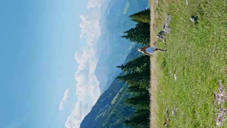 Vista-Trasera-Vertical-De-Una-Chica-Con-Falda-Blanca-Caminando-Sobre-Pastos-En-Las-Montañas-De-Austria-Durante-El-Verano