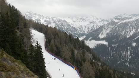 Static-establishing-shot-of-people-skiing-down-slope-in-snowy-Dolomite-alps