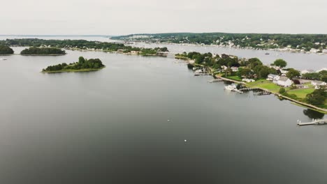 Aerial-view-of-coastal-town-with-sail-boats-and-vessels-over-bay-water-approaching-bridge-in-New-England