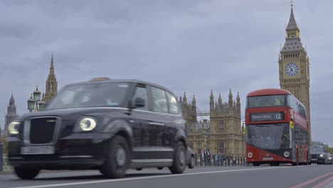 Red-double-decker-buses-an-taxi-crossing-Westminster-Bridge-with-Houses-of-Parliament-and-Big-Ben-in-background,-London-in-UK