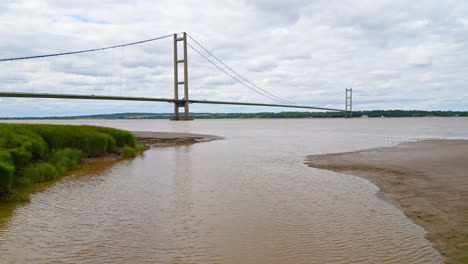 A-drone's-view-of-Humber-Bridge,-12th-largest-suspension-span-on-Earth,-stretches-over-River-Humber,-linking-Lincolnshire-to-Humberside-with-traffic