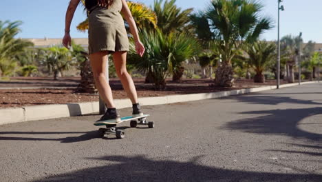 Amidst-the-tranquility-of-palm-trees-and-the-beach,-a-young-girl's-longboard-journey-is-showcased-in-slow-motion,-embodying-both-beauty-and-relaxation