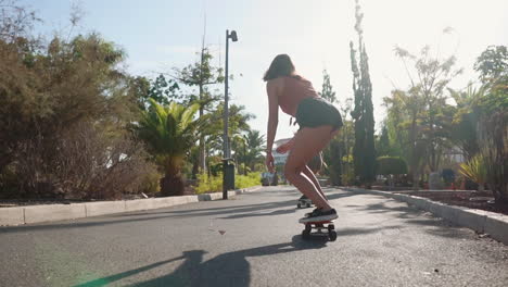 Two-young-Hispanic-women-skateboard-at-a-leisurely-pace-on-island-paths,-enveloped-by-the-sunset's-glow-and-palm-trees.-This-portrayal-of-slow-motion-joy-embodies-well-being-and-happiness