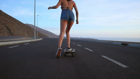 Young-ginsana-skateboards-on-the-road-against-a-backdrop-of-great-mountains-and-sky