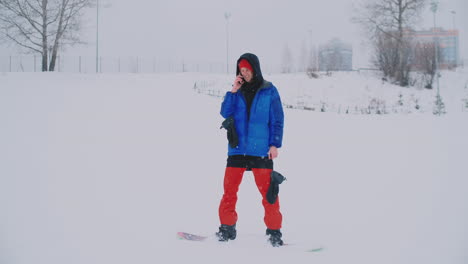 Männlicher-Snowboarder-In-Blauer-Jacke-Wird-Live-Von-Ihrem-Smartphone-Im-Skigebiet-übertragen