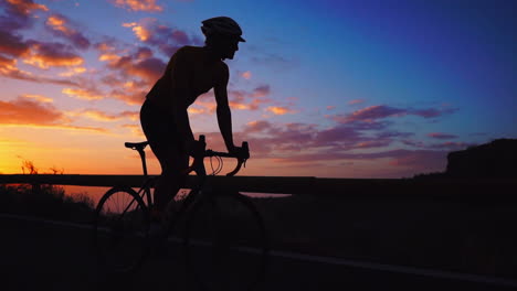 Silhouette-Slow-motion-captures-the-athlete-navigating-a-mountain-serpentine-on-a-bike,-taking-pleasure-in-the-island's-view,-representing-a-commitment-to-a-healthy-lifestyle-at-sunset