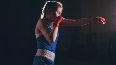 Beautiful-woman-fighter-in-red-bandages-conducts-a-shadow-fight-while-exercising-in-the-gym.-Slow-motion.-steadicam-shot