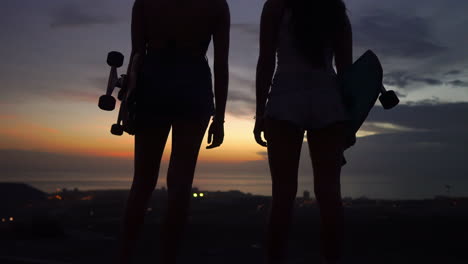Girlfriends-appreciate-the-picturesque-sunset-sky-vista-following-their-mountain-skateboarding