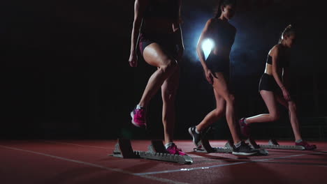 Young-female-runner-athlete-with-smartwatch-ready-to-sprint-at-running-track-starting-line