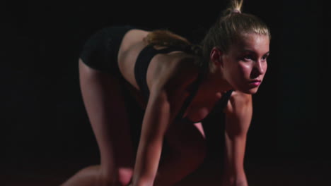 Professional-woman-athlete-on-a-dark-background-gotovtes-to-run-the-sprint-of-Jogging-shoes-in-sneakers-on-the-track-of-the-stadium-on-a-dark-background.-Close-up