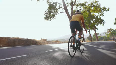 Engaging-in-outdoor-exercise,-a-man-cycles-on-an-empty-morning-road-with-his-road-bike.-The-slow-motion-recording-emphasizes-the-concept-of-extreme-sports