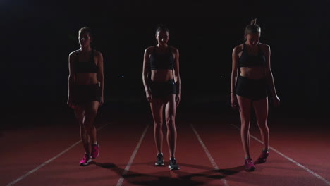 Drei-Mädchen-In-Schwarzer-Kleidung-Stehen-In-Den-Startlöchern,-Um-Im-Licht-Der-Lichter-Das-Rennen-Des-Wettbewerbs-Zu-Starten-Und-In-Richtung-Ziel-Zu-Rennen