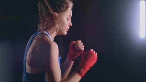 Female-boxer-training-in-dark-room-with-backlight-in-slow-motion-side-view.-steadicam-shot