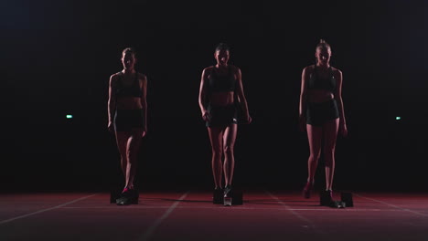 Young-female-runner-athlete-with-smartwatch-ready-to-sprint-at-running-track-starting-line