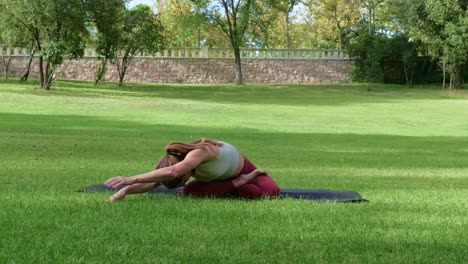 Flexible-woman-doing-forward-bend-in-park