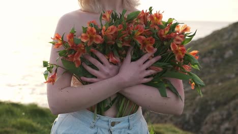 Mujer-Anónima-Con-Flores-Cerca-Del-Mar