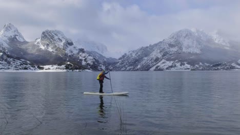 Man-on-paddle-board-between-water-and-mountains-on-coast