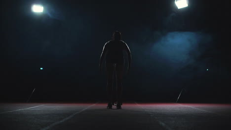 Professional-woman-athlete-on-a-dark-background-gotovtes-to-run-the-sprint-of-Jogging-shoes-in-sneakers-on-the-track-of-the-stadium-on-a-dark-background.-Average-plan