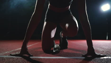 Professional-woman-athlete-on-a-dark-background-gotovtes-to-run-the-sprint-of-Jogging-shoes-in-sneakers-on-the-track-of-the-stadium-on-a-dark-background.-Close-up