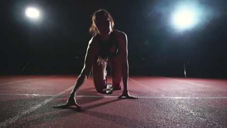 Professional-woman-athlete-on-a-dark-background-gotovtes-to-run-the-sprint-of-Jogging-shoes-in-sneakers-on-the-track-of-the-stadium-on-a-dark-background.-Close-up