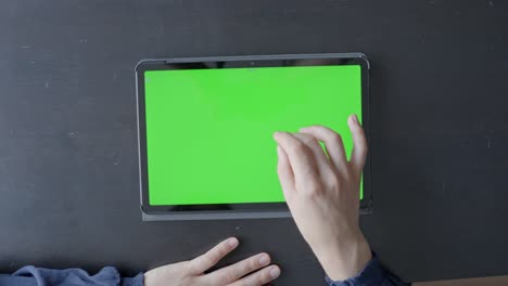 Hand-of-person-touching-table-with-green-screen,-top-down-view