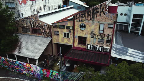 Aerial-tracking-shot-in-front-of-graffiti-covered-buildings-in-the-Beco-do-Batman-Alley,-in-cloudy-Vila-Madalena,-Sao-Paulo,-Brazil