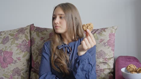 Beautiful-girl-eating-delicious-chocolate-cookies-in-her-home,-portrait-view