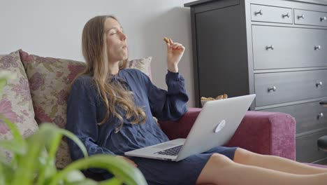 Attractive-woman-takes-break-from-work-and-eats-cookie-in-home-office
