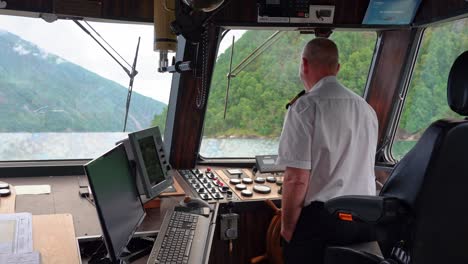 Capitán-De-Un-Barco-Turístico-Por-El-Fiordo-Noruego-Sonriendo-Y-Riendo-A-La-Cámara-Desde-La-Timonera-Mientras-Navega-Por-Sognefjorden