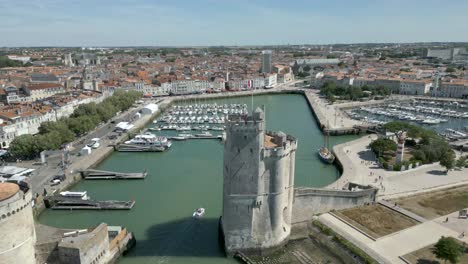 Cinematic-aerial-view-of-the-old-port-of-La-Rochelle-and-the-Saint-Nicolas-tower-with-the-French-flag-fluttering-in-the-wind,-France