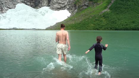Vater-Und-Sohn-Laufen-In-Eiskaltes-Gletscherwasser-Unterhalb-Des-Boyabreen-Gletschers-In-Fjaerland-Norwegen---Zeitlupe