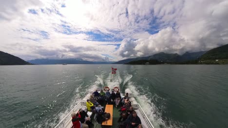 Impresionante-Vista-De-Popa-Del-Crucero-En-Barco-Turístico-Sognefjorden-Noruega-Con-Gente-Feliz-Afuera-Y-La-Bandera-De-Noruega-En-La-Parte-Trasera-Del-Barco---Gran-Angular