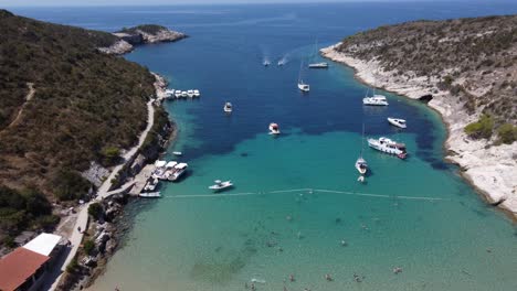 People-relaxing-at-sandy-Porat-beach-in-Bisevo-Island,-boats-anchored-offshore,-clear-water-croatia