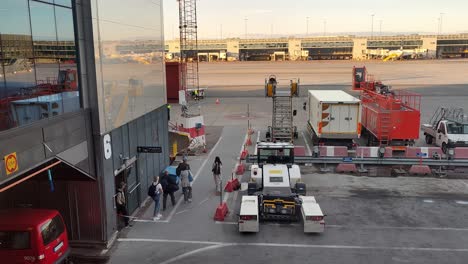 People-exit-gate-6-outside-on-Arlanda-airport-terminal-and-walking-to-board-their-airplane-at-sunset---Static-airport-clip-looking-out-window