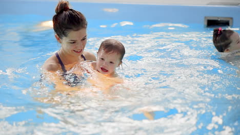 Baby-Im-Pool-Springt-Von-Der-Seite-Ins-Wasser-Und-Schwimmt-In-Zeitlupe-Zu-Seiner-Mutter