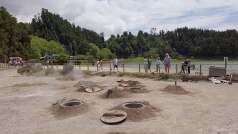 Tourists-watching-the-emptied-cooking-pits-where-the-local-dish-"-Cozido-Das-Furnas"-is-cooked-by-the-steam-of-volcanic-hot-springs-at-Lake-Furnas,-San-Miguel-Island,-Azores,-Portugal---July-2023