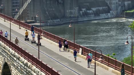 Auf-Der-Fußgängerbrücke-In-Minneapolis-Laufen,-Rennen,-Besichtigen-Und-Fahren-Segways