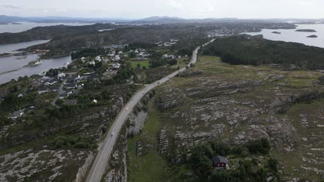 Coches-Circulando-Por-La-Carretera-En-Øygarden,-Noruega,-Cerca-De-Bergen,-Con-Un-Barrio-Caro-Al-Lado-De-La-Carretera-Y-Una-Hermosa-Naturaleza.